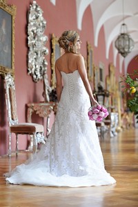 Svatební fotografie nevěsty v bílých šatech a růžovou svatební kyticí na zámku v Častolovicích