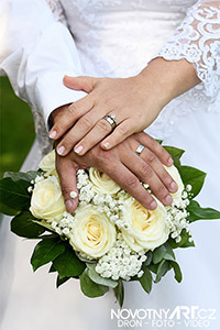 Svatební prstýnky novomanželů se svatební kyticí žlutých růží